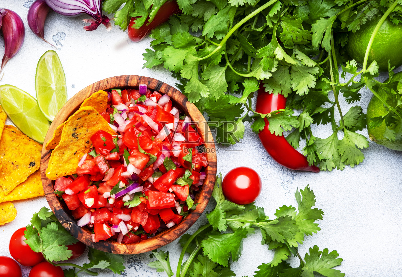 莎莎酱配番茄、辣椒、洋葱、大蒜和香菜,配玉米片。墨西哥食物。白色桌面背景,俯视图照片摄影图片