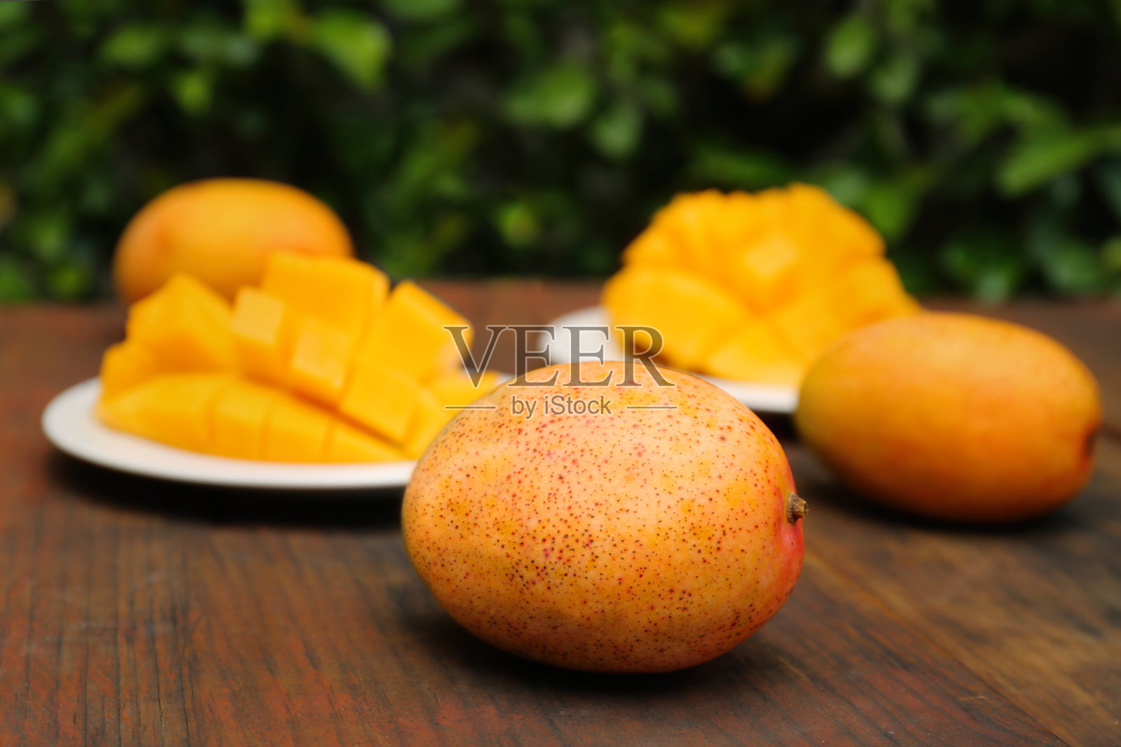 在户外的木桌上,美味的成熟的完整的芒果和切好的芒果照片摄影图片