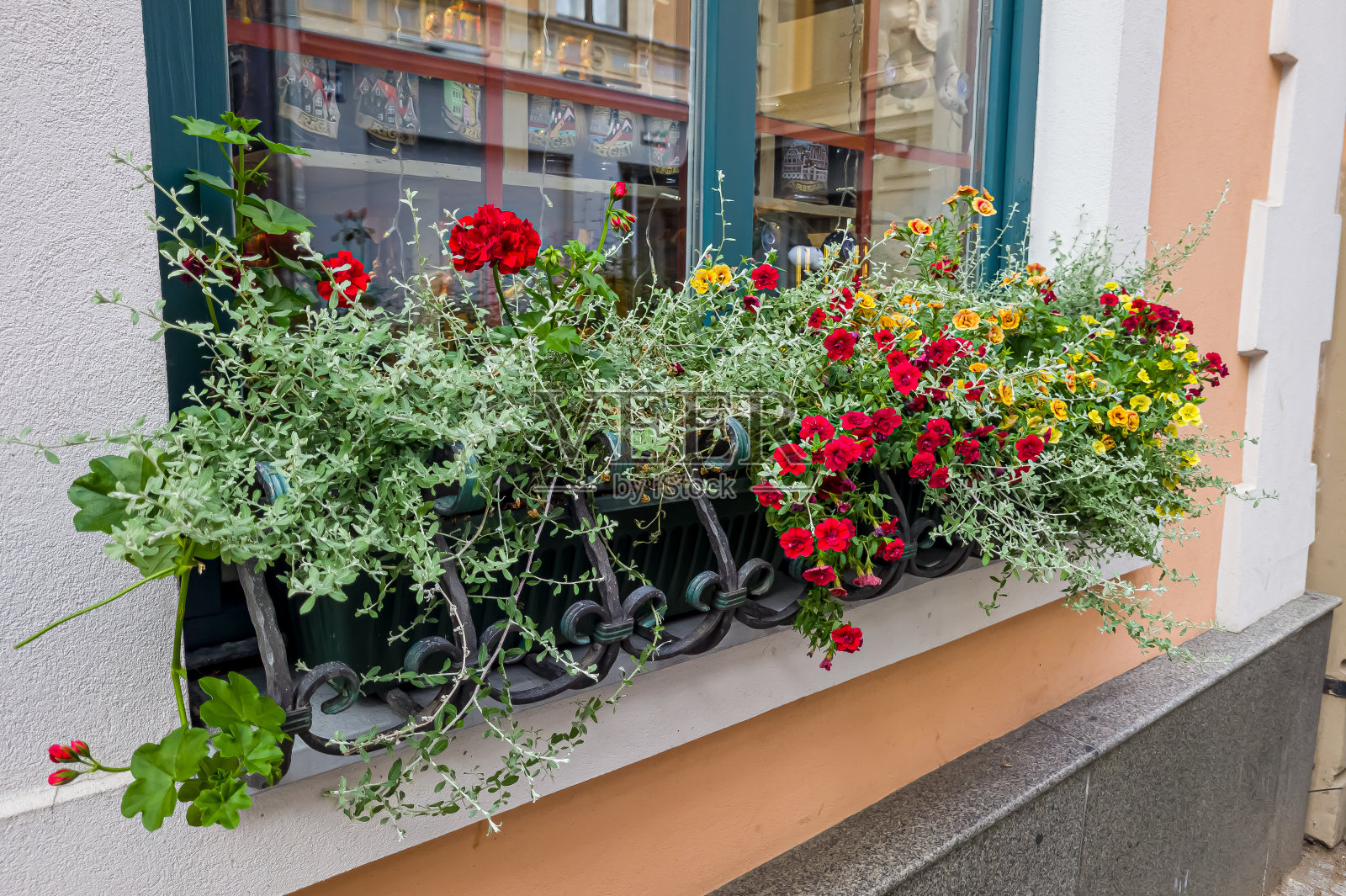 住宅窗台上的盒子里的花。一座红砖房子。红砖墙上的一扇窗户,外面的窗台上放着盆花。靠红砖墙的盆栽植物照片摄影图片