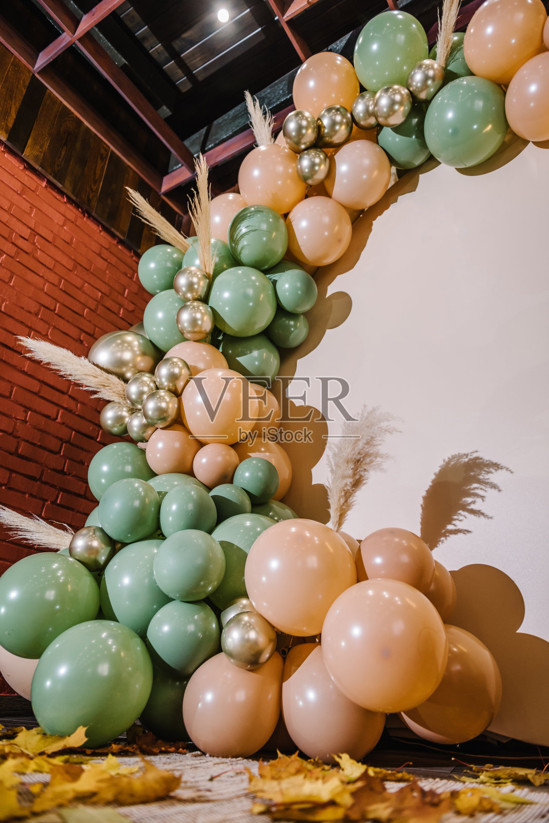 细节时髦的秋季装饰。拱门上装饰着绿色、棕色、金色的气球、干树叶,用于婚礼仪式。生日宴会的接待。庆祝洗礼。照片墙装饰文字空间。照片摄影图片
