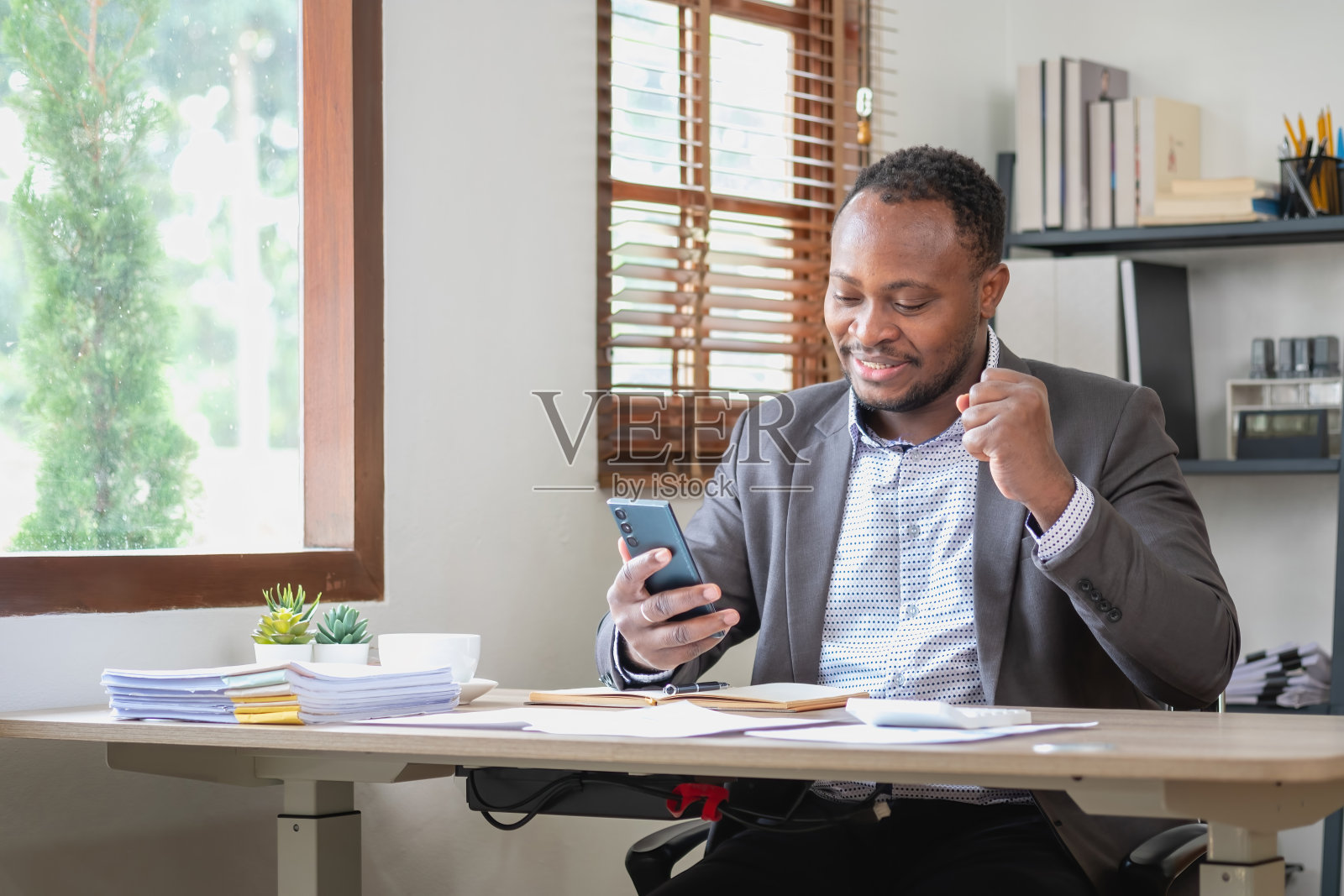 非洲裔美国黑人在智能手机和笔记本电脑上阅读公司业绩时很开心。商业金融和技术概念。照片摄影图片