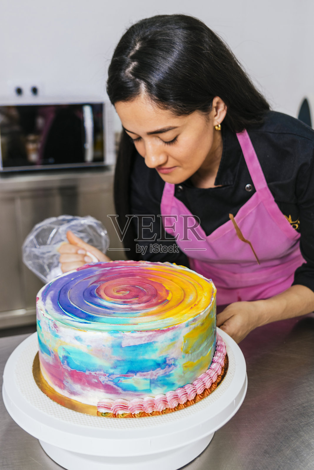 糕点师用裱花袋装饰五彩蛋糕照片摄影图片