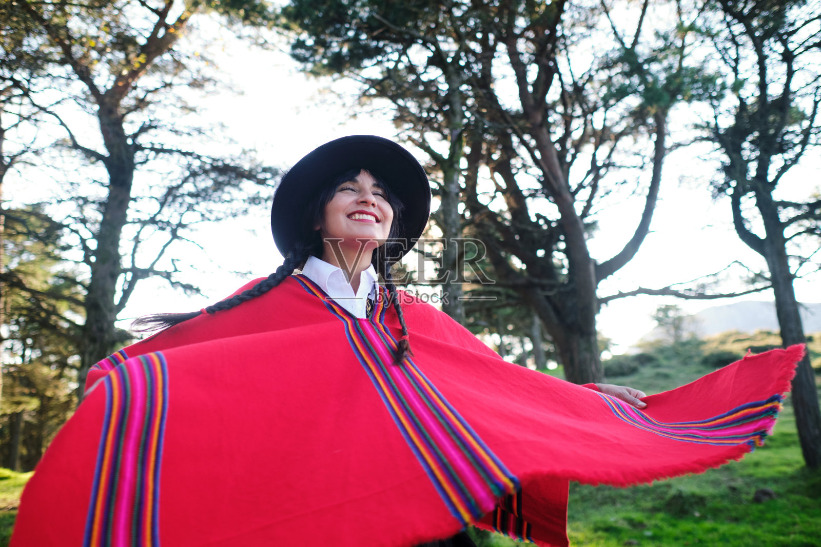 厄瓜多尔年轻女子微笑着在森林里举起她的地方斗篷照片摄影图片