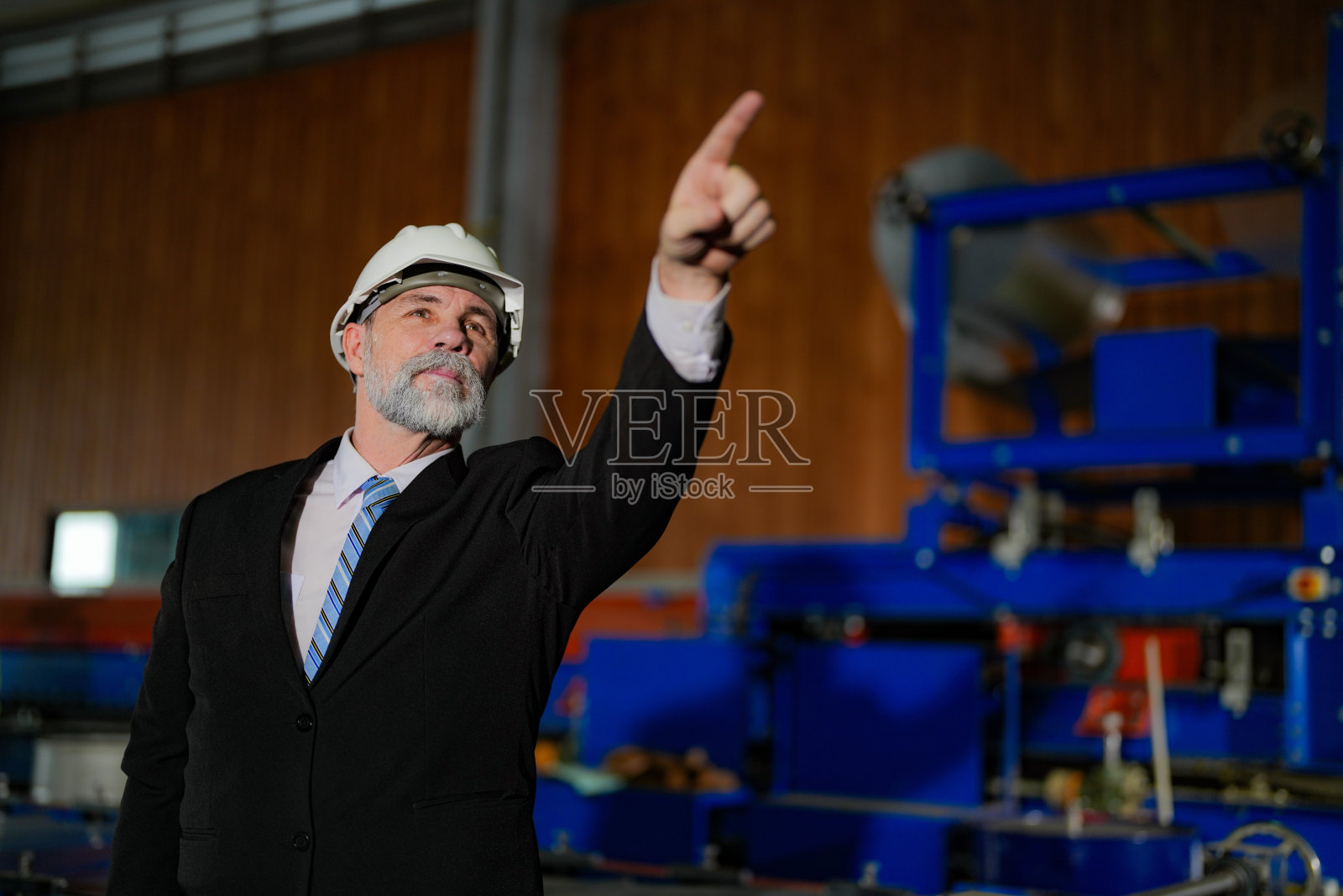 肖像工程师老年老板自信地站在工业工厂里。智能工业运维理念。满脸胡子的老工程师站着。照片摄影图片