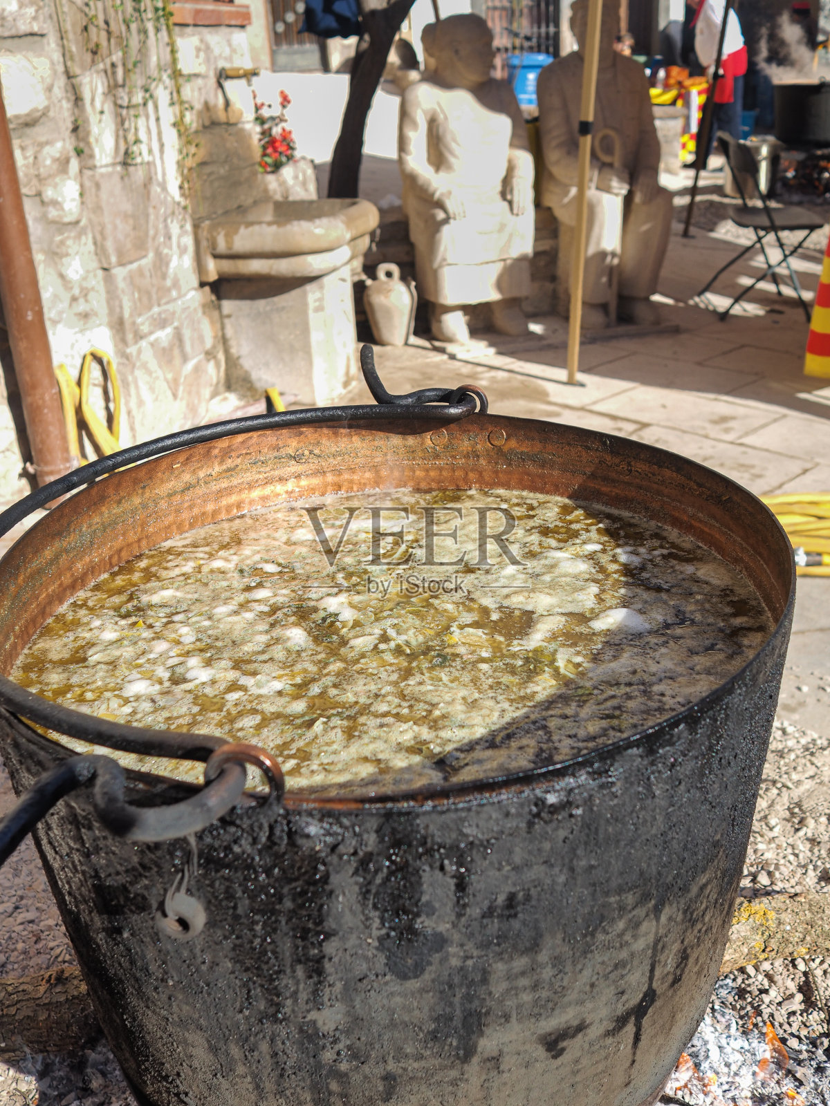 在西班牙加泰罗尼亚的传统中世纪集市上,人们正在准备肉和热蔬菜汤。照片摄影图片