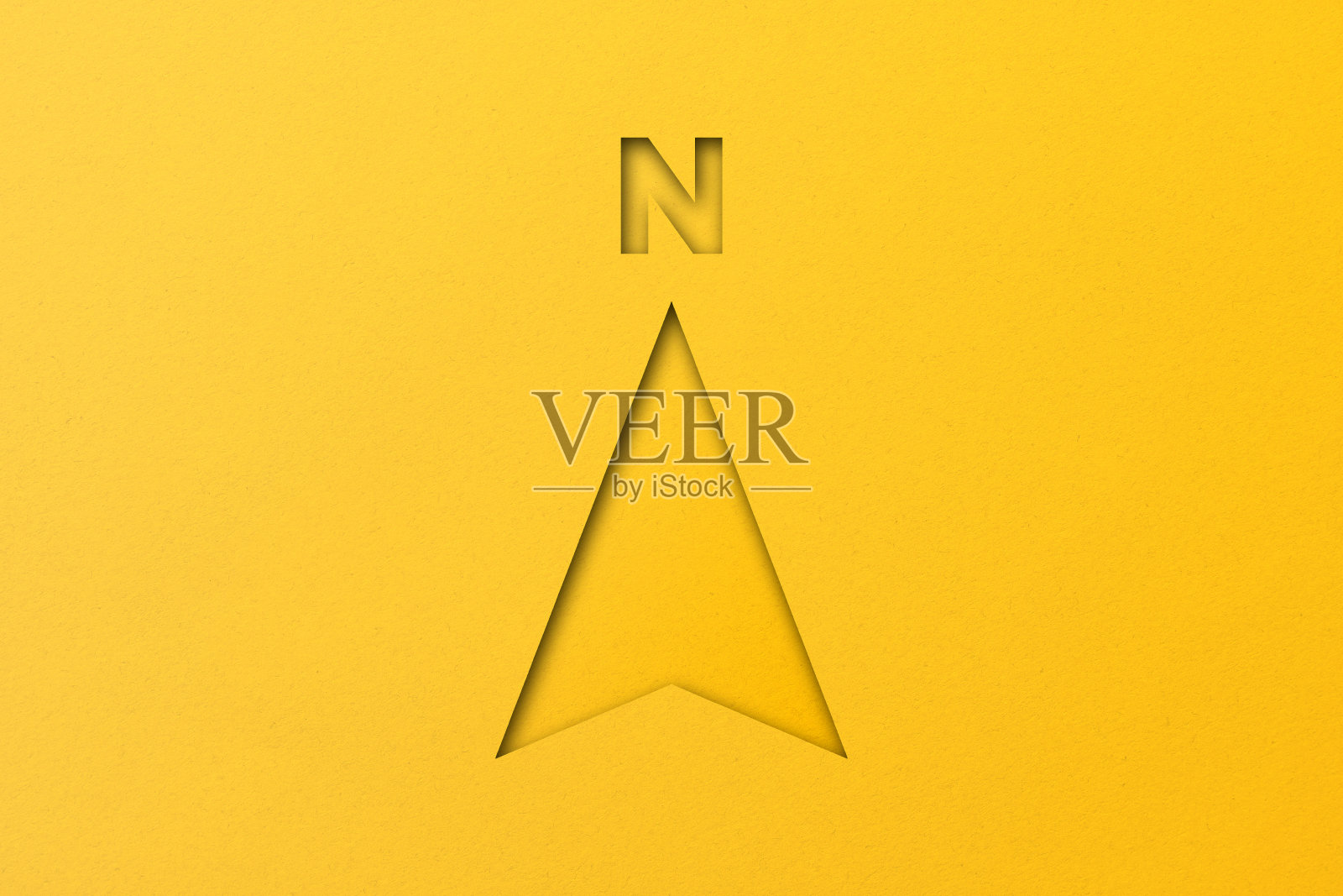 黄纸裁成形状,黄纸背景上有北箭头。照片摄影图片