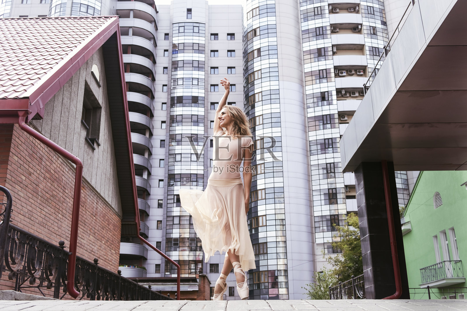 夏日里,一名芭蕾舞女演员在街上摆着足尖姿势,展示芭蕾舞的元素照片摄影图片