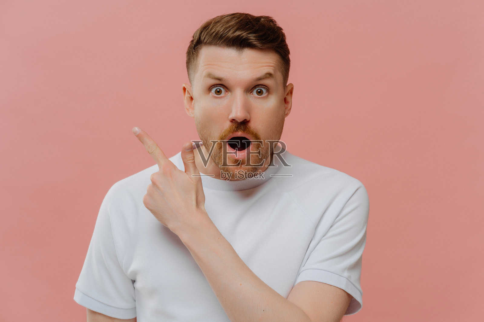 震惊的年轻人用手指向一边,脸上带着惊讶的表情照片摄影图片