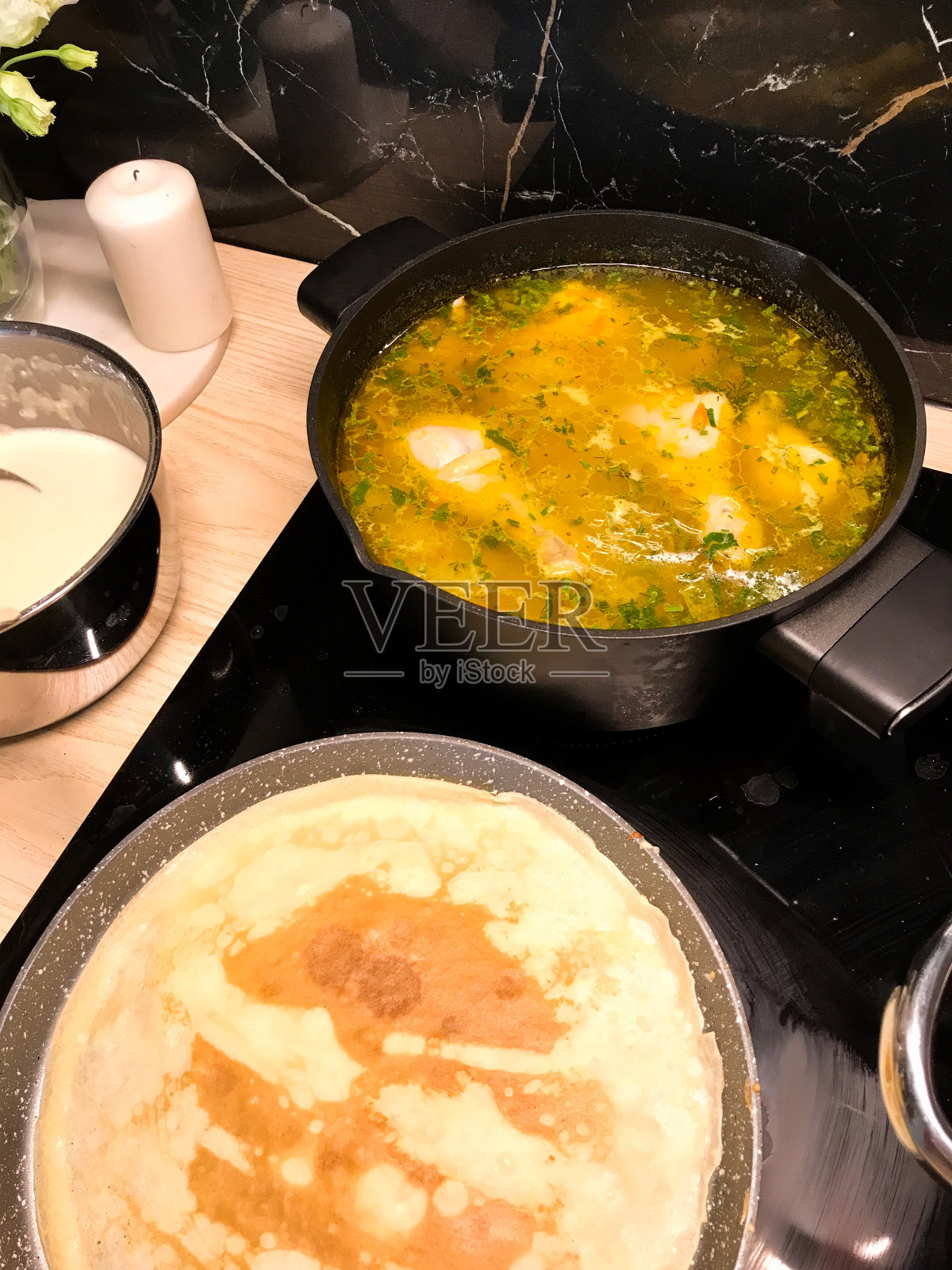 在厨房里,在平底锅里煮大牛奶煎饼和在锅里煮美味汤的过程照片摄影图片