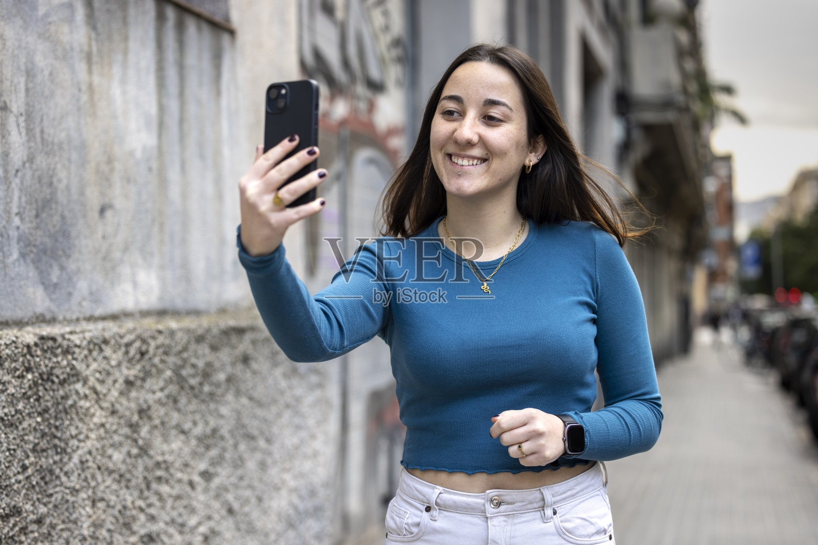 年轻女性,z世代,在巴塞罗那的城市环境中使用她的手机。照片摄影图片
