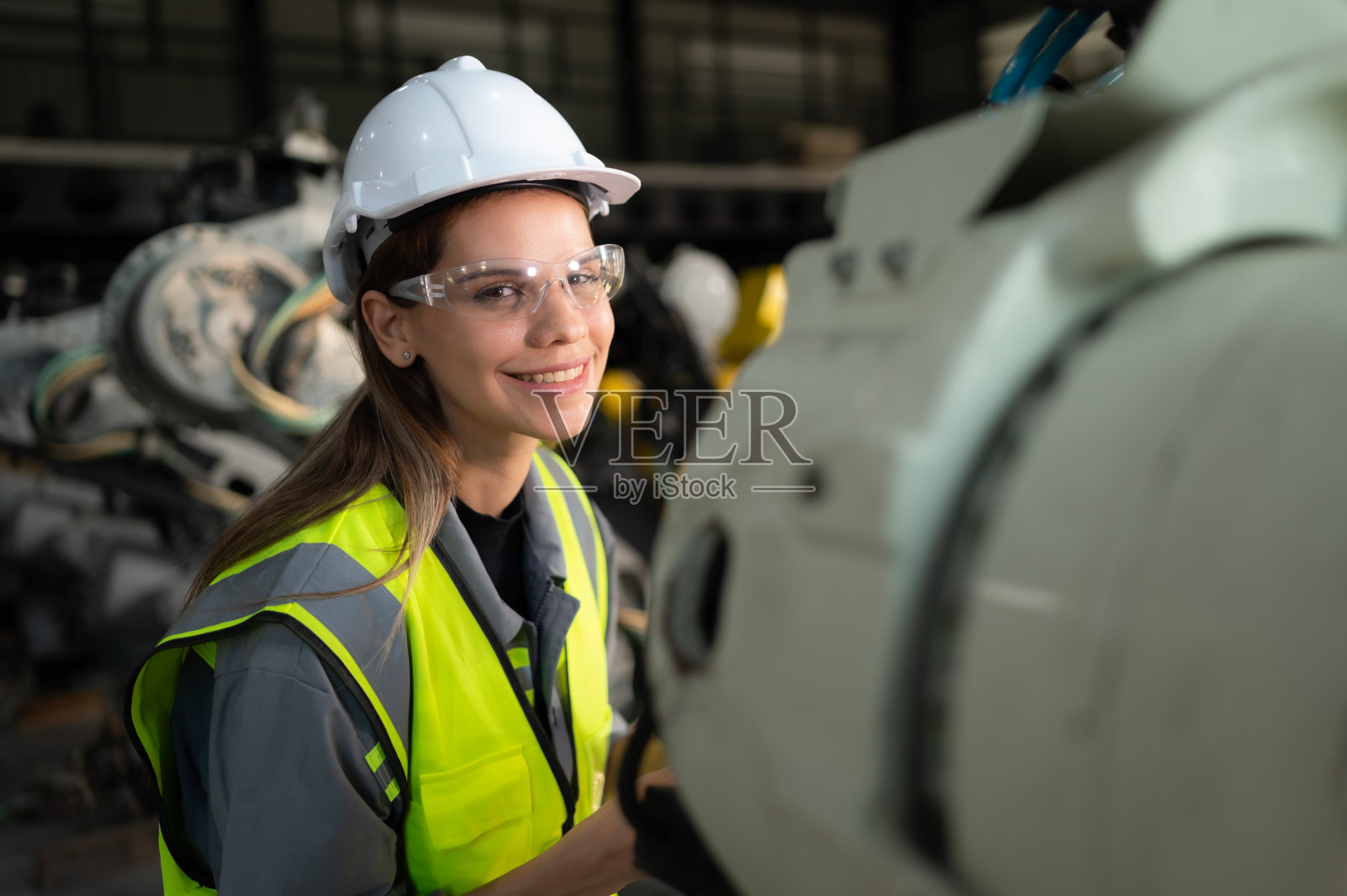 在机器人仓库里,女工程师正在开心地更新软件和校准机器人手臂。照片摄影图片