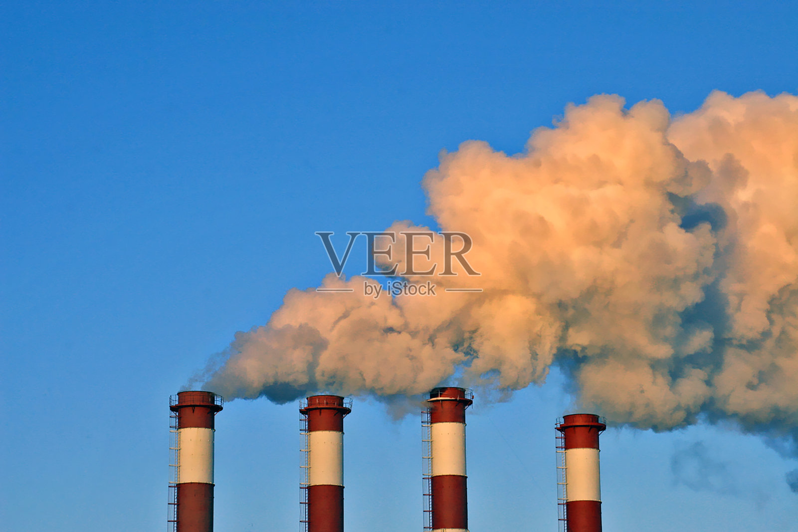 工业烟囱冒着白烟,映衬着蓝天。照片摄影图片