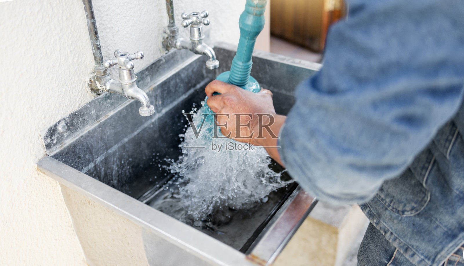 Plumber, water and man with plunger for kitchen sink, maintenance and repairs, blockage or cleaning. Plumbing, drain and professional handyman fixing, clear and working with equipment for system fix照片摄影图片