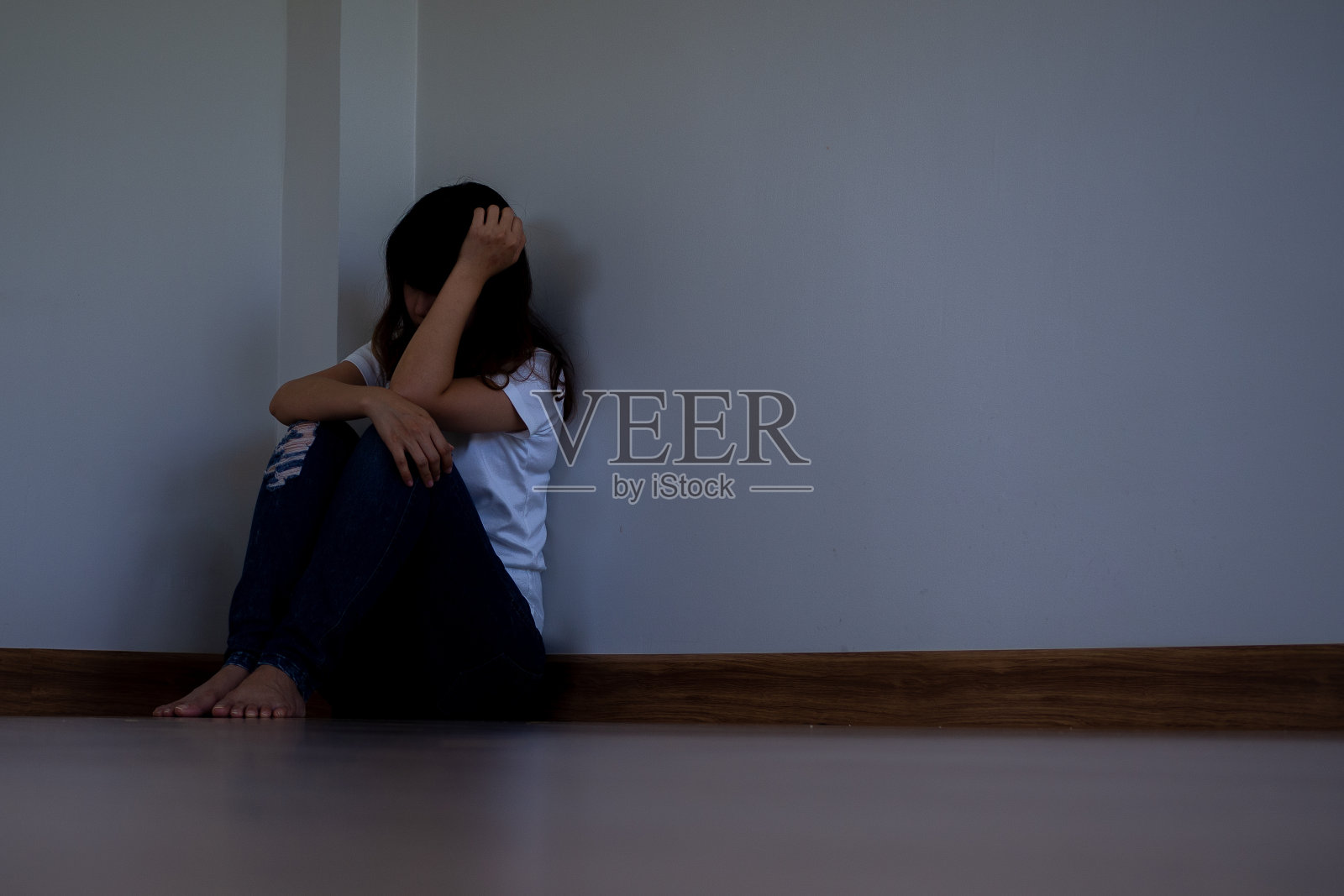 女孩坐在房间的角落里抱着头照片摄影图片