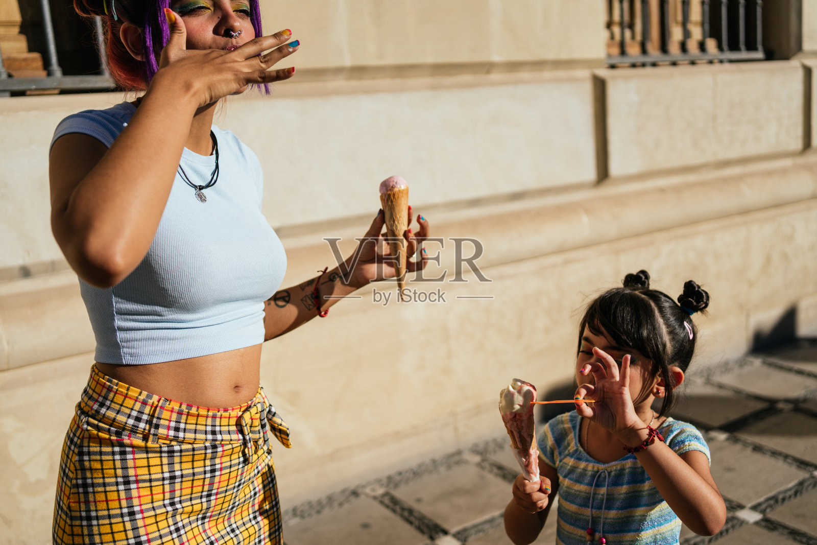 女孩和她妈妈在街上吃冰淇淋。照片摄影图片