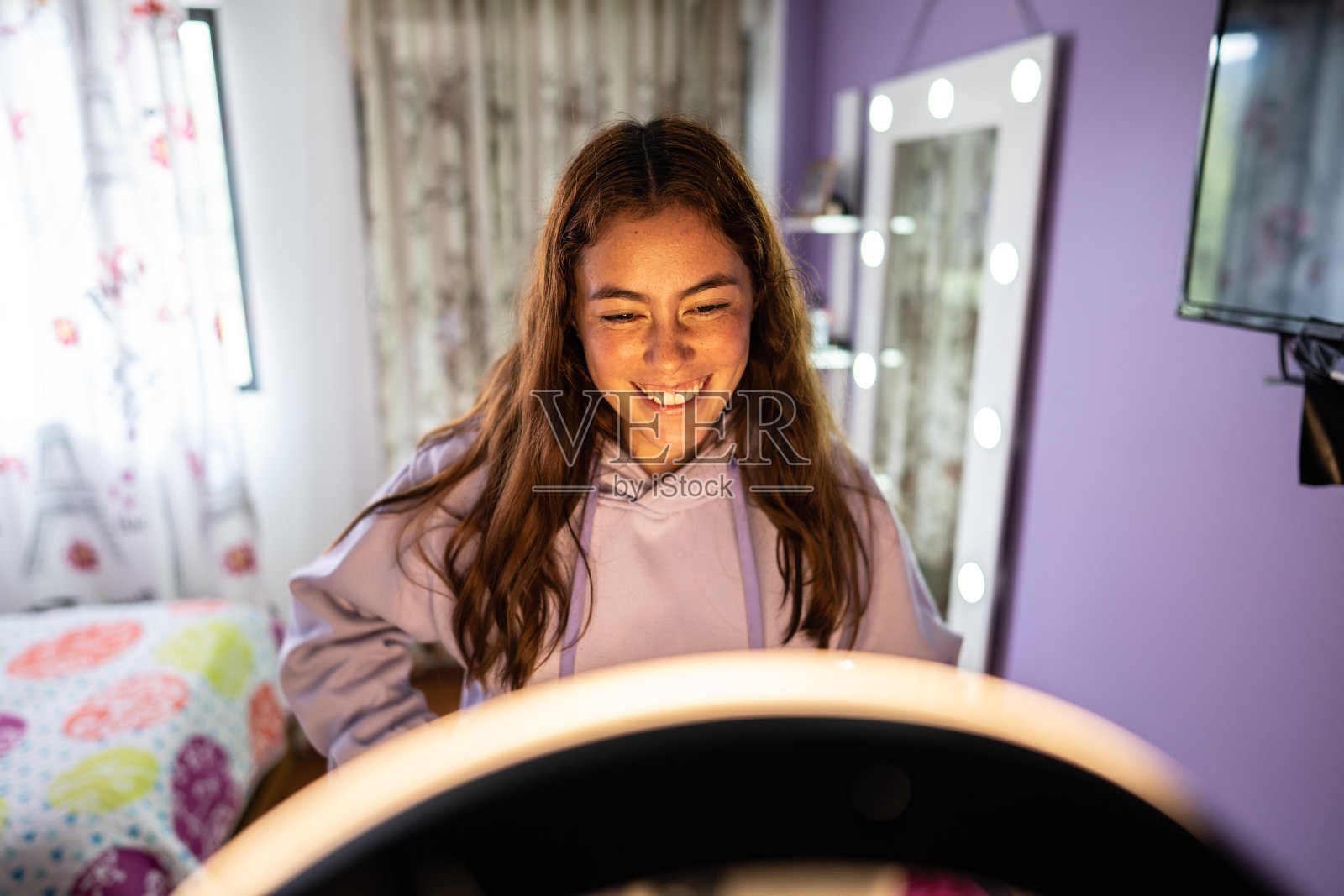 年轻女子在家里的卧室里用戒指灯为社交媒体直播照片摄影图片