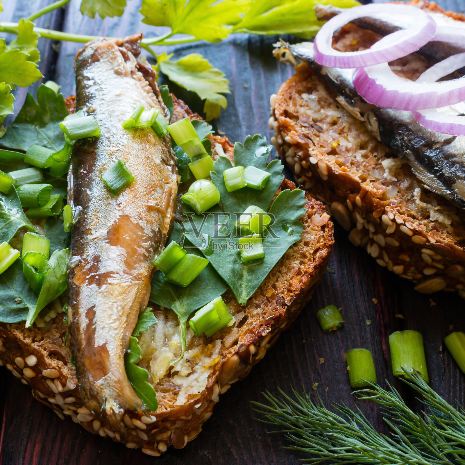 面包上放沙丁鱼,欧芹叶上撒洋葱照片摄影图片