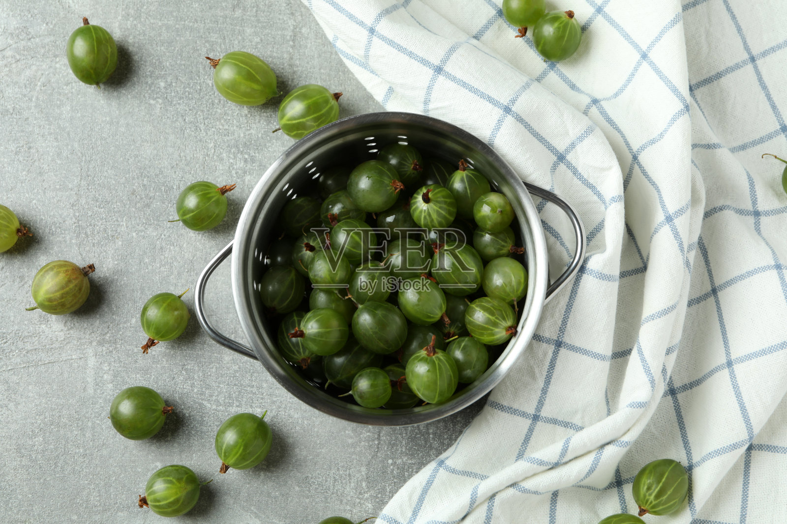 一锅熟醋栗和厨房毛巾在灰色纹理的桌子上照片摄影图片