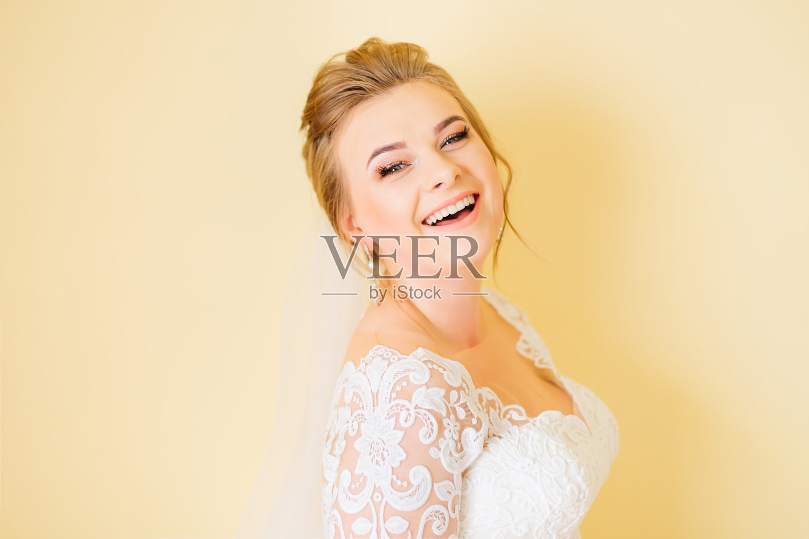 幸福的新娘微笑着看着镜头。白色婚纱照片摄影图片