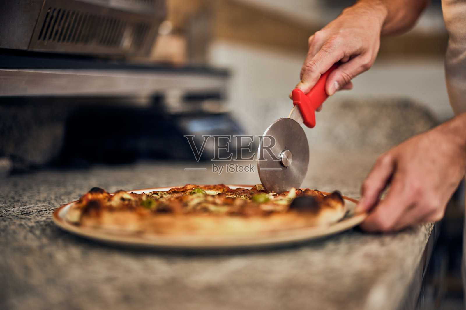 美味披萨的特写,男人用披萨刀切披萨。照片摄影图片