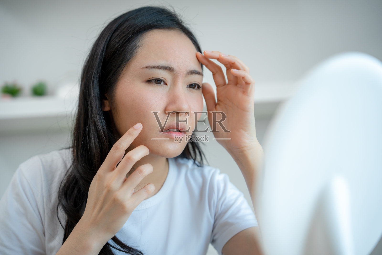 年轻的亚洲女性担心自己的脸,皮肤病和对化妆品中的类固醇过敏。敏感皮肤,因晒伤而红肿的脸,痤疮,对化学物质过敏,脸上出现皮疹。皮肤问题与美容照片摄影图片