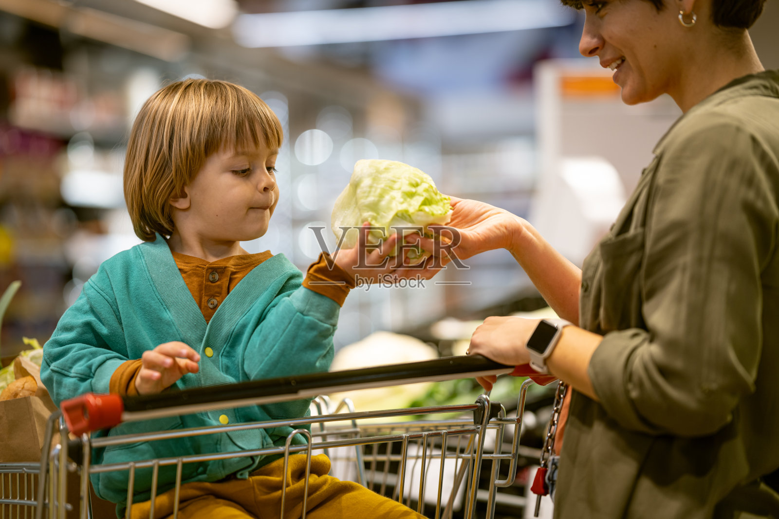 一位母亲和她的儿子在买蔬菜和水果。照片摄影图片