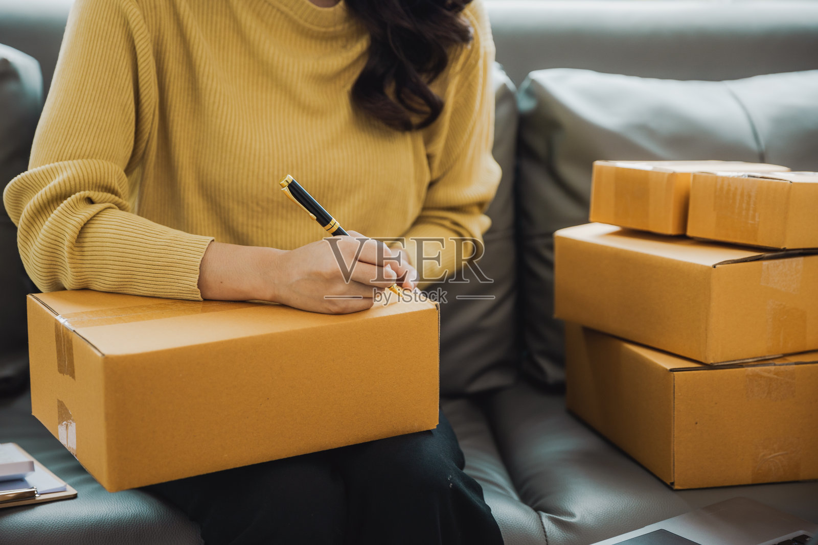 一个独立的亚洲女性使用笔记本电脑和盒子的特写。开朗成功的网络营销包装盒和发送中小企业的概念照片摄影图片