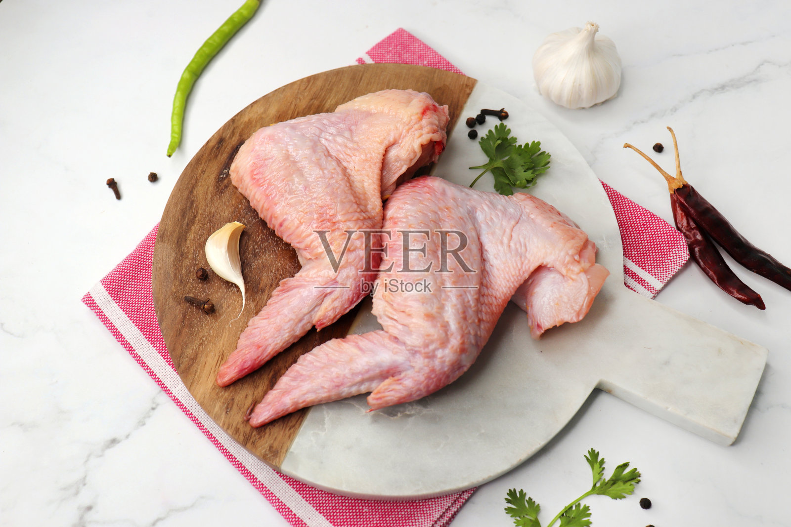 生鸡翅放在黑色盘子里,配上黑胡椒、绿辣椒、红辣椒和香菜等香料。非常适合做布法罗鸡翅副本的空间。照片摄影图片