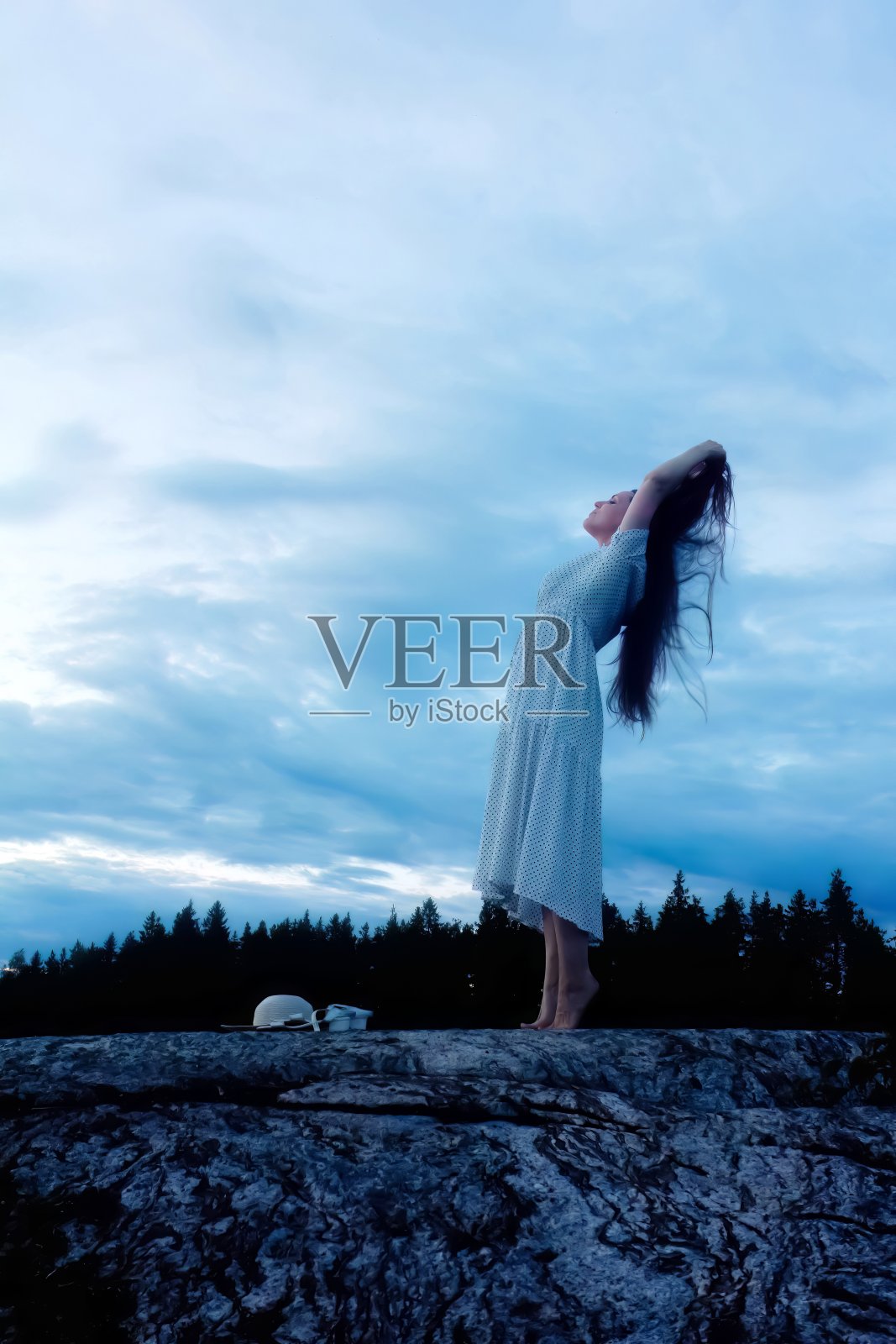 夕阳下,年轻女子在岩石上跳舞照片摄影图片