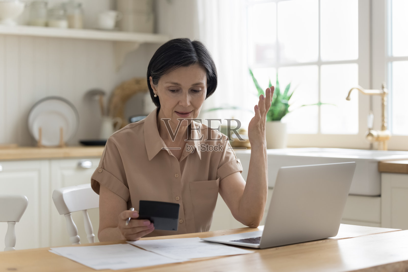 忧心忡忡的成熟女房主在计算器上计算开支照片摄影图片