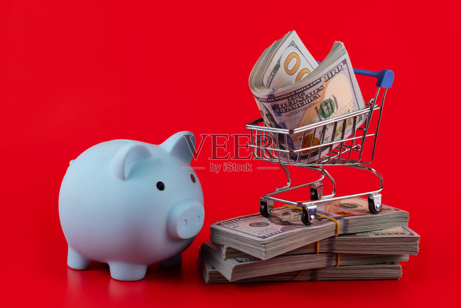 红色背景的超市里的微型购物车里放着100美元照片摄影图片