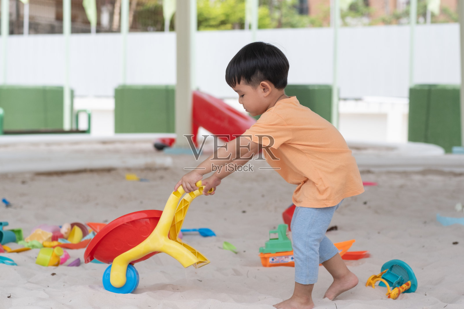 孩子亚洲男婴微笑有快乐的乐趣玩玩具在沙地或沙坑或操场或沙地照片摄影图片