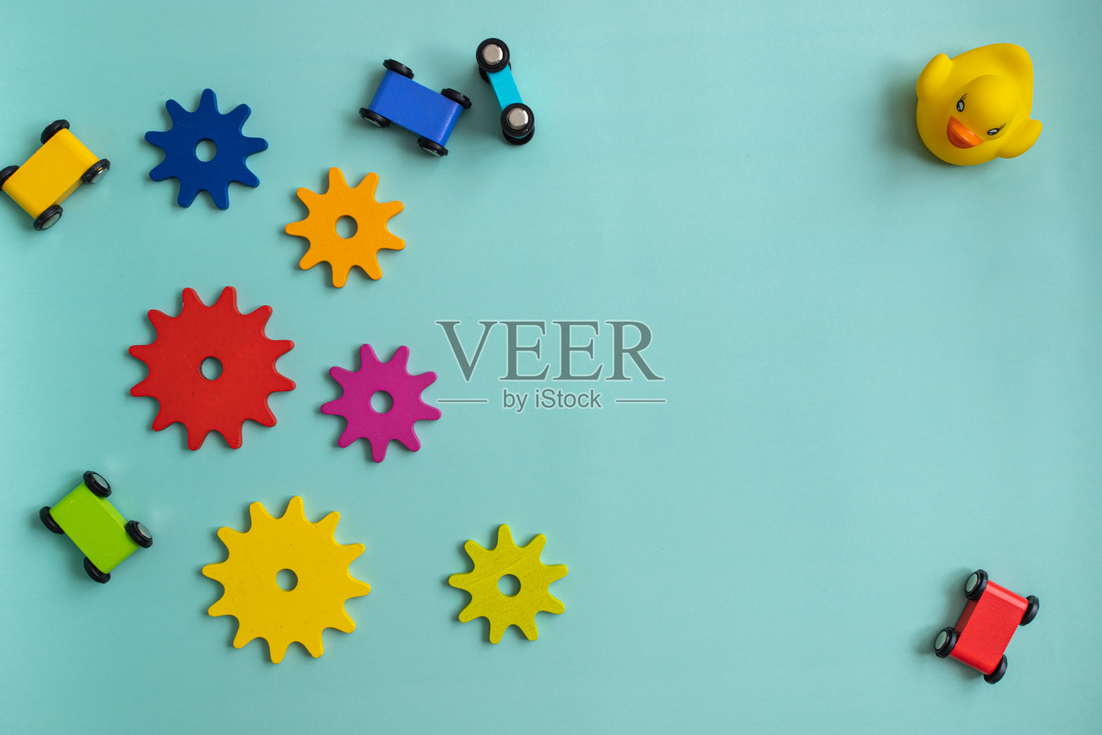 俯视图特写,背景是蓝绿色背景上的儿童玩具,多色齿轮,汽车,鸭子,轮椅,带钉子的球照片摄影图片