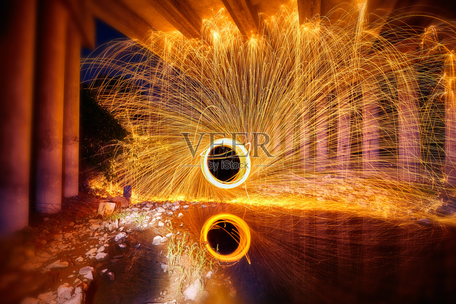 钢丝绒反射在混凝土桥下的水中,发出黄色和白色的火花照片摄影图片