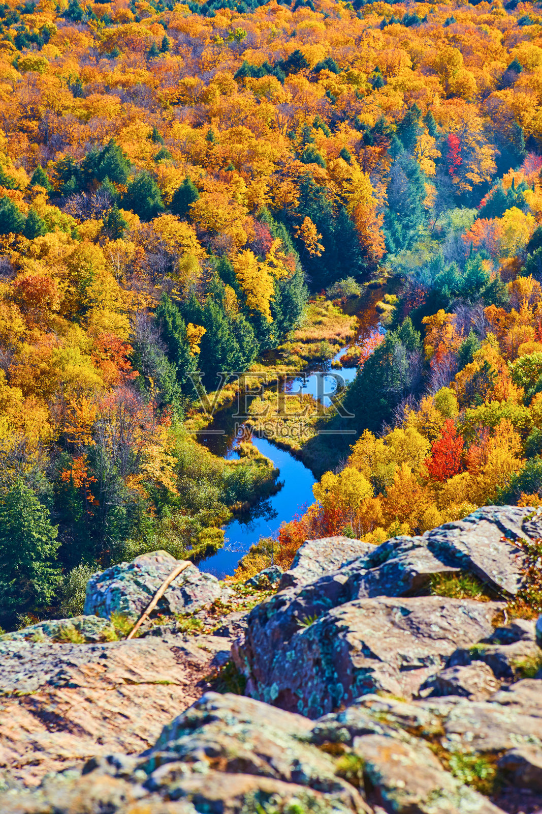 蜿蜒的河流消失在露出地面的岩石下,秋天被森林包围照片摄影图片