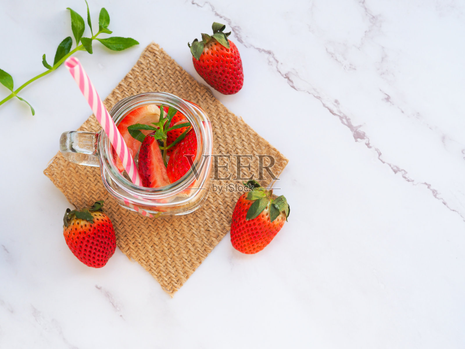俯视图,大理石背景上注入了新鲜有机草莓和吸管的水。为你的文字留出空间。照片摄影图片
