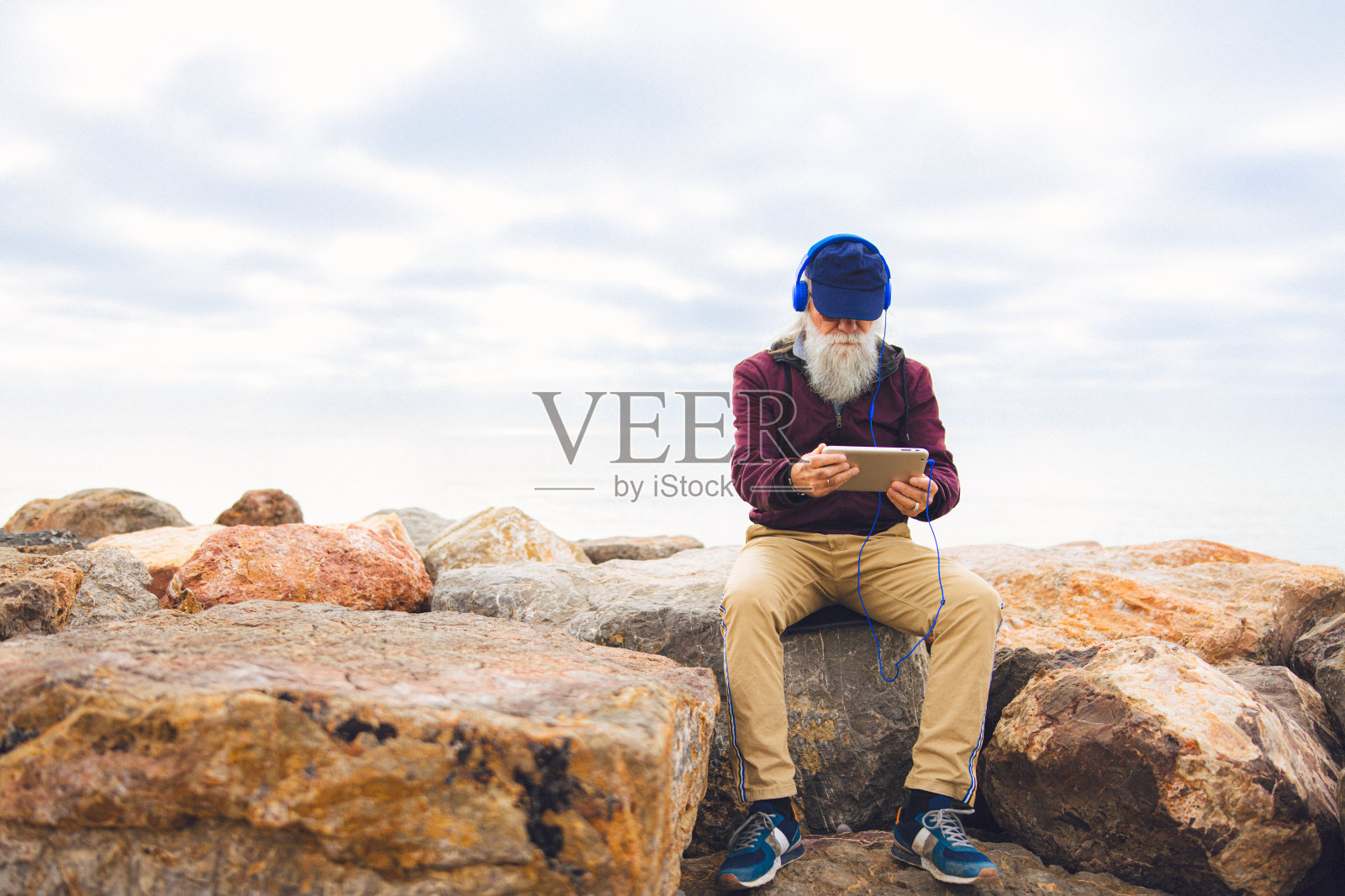 一位年长的成年男性在海边使用他的数码平板电脑照片摄影图片