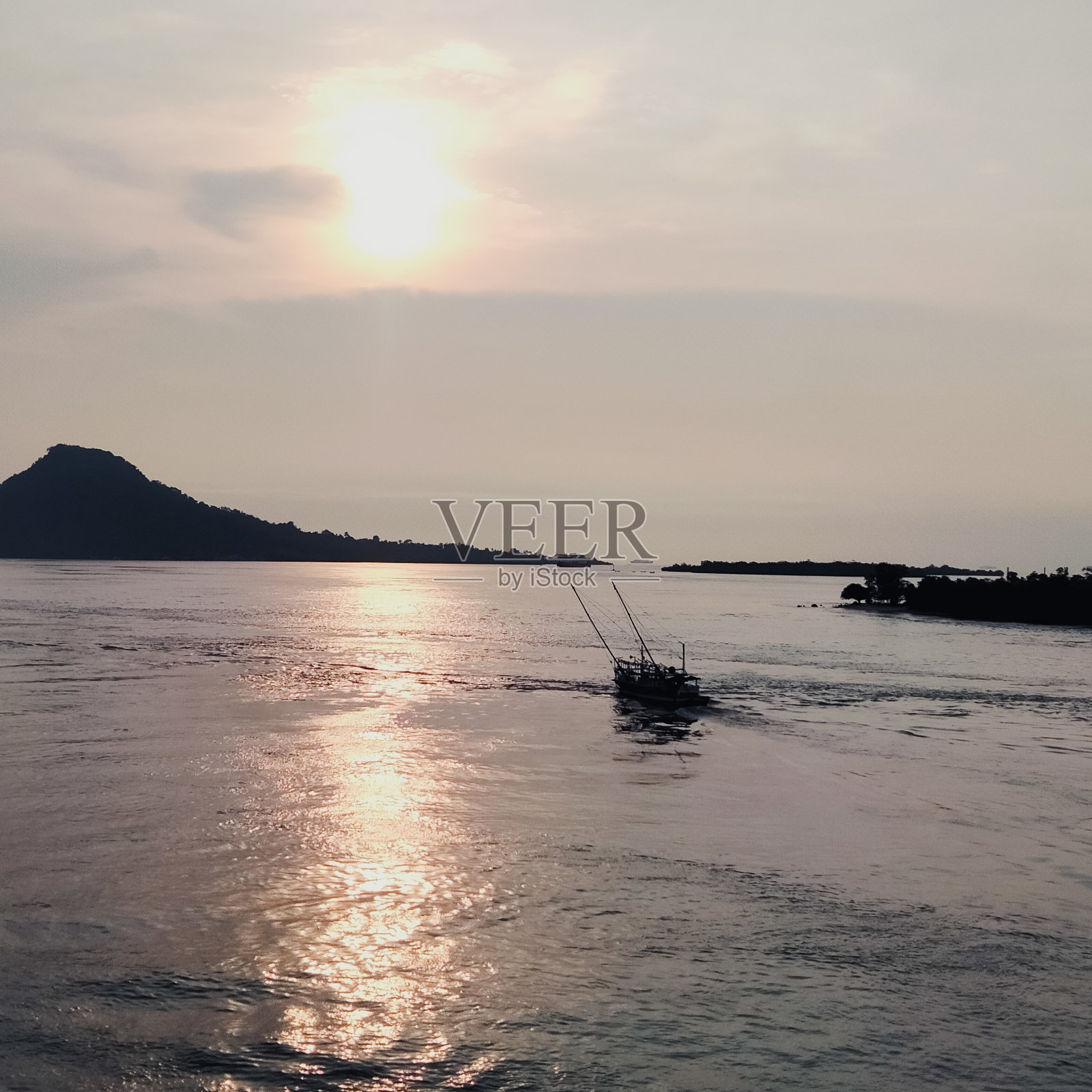 一艘船航行在海洋中央,有一个美丽的岛屿装饰照片摄影图片