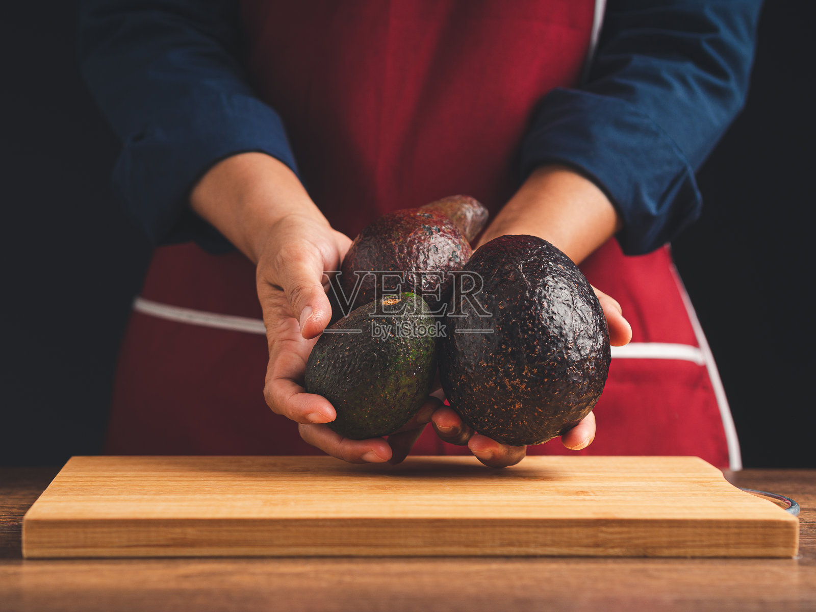 站在厨房里,手拿三个牛油果的特写。照片摄影图片