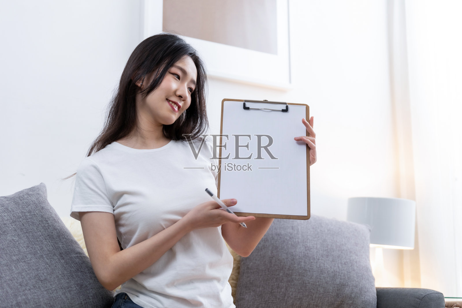 拿着写字板坐在办公室沙发上工作的女性照片摄影图片