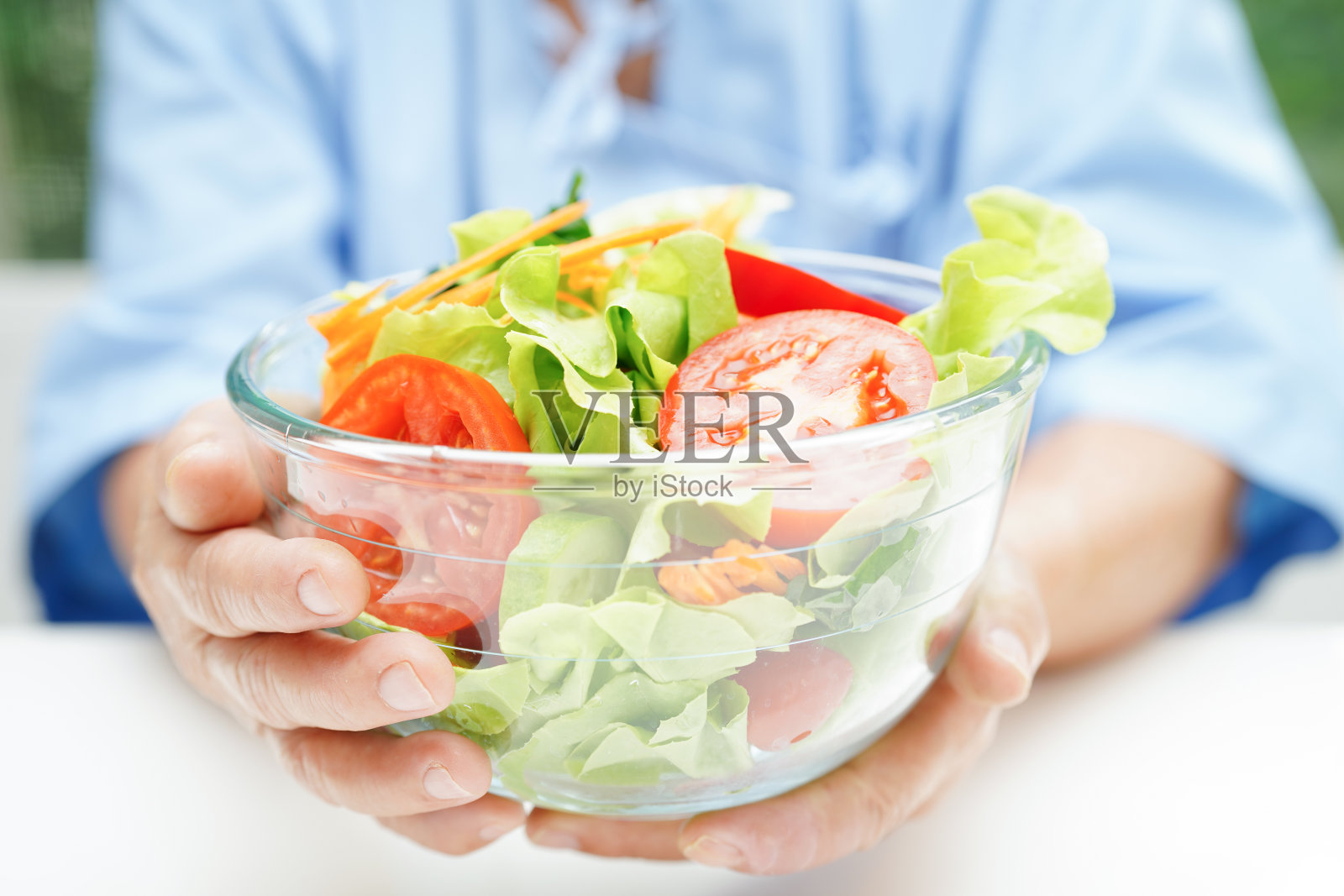 亚洲老年妇女病人在医院吃鲑鱼排和蔬菜沙拉作为健康食品。照片摄影图片