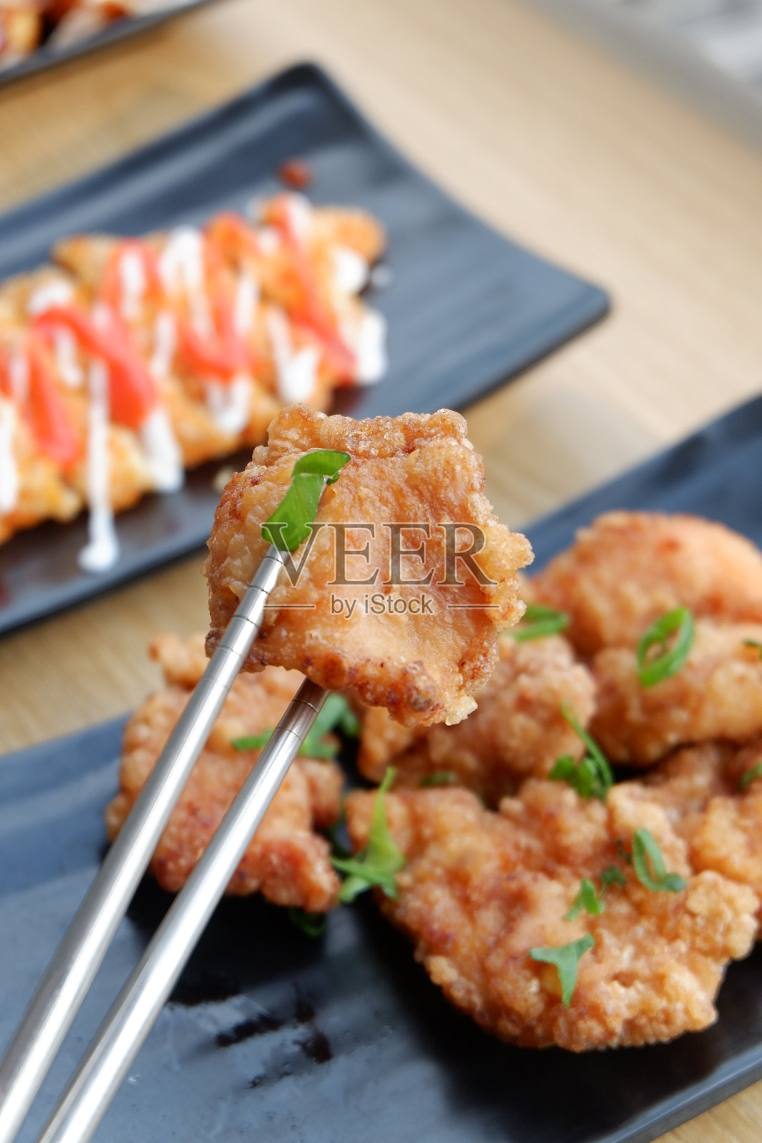 用筷子夹起一块酥脆的炸鸡照片摄影图片