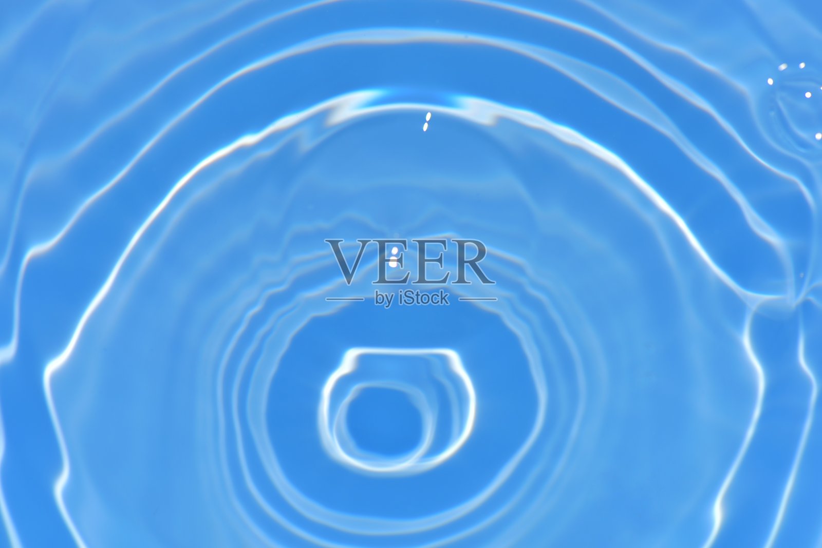 蓝蓝的水面上泛起涟漪。散焦模糊透明蓝色透明平静水面纹理与飞溅和气泡。水波与闪亮的图案纹理背景。照片摄影图片