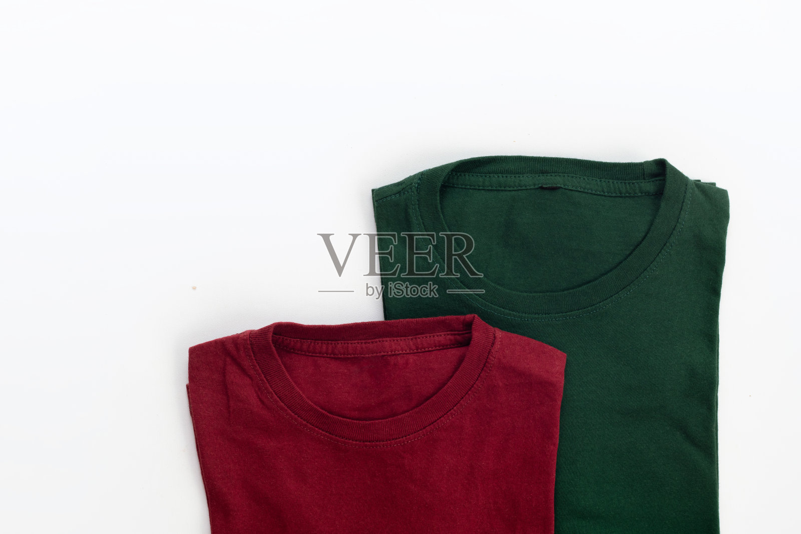 折叠黑色,暗红色和绿色t恤,白色背景照片摄影图片