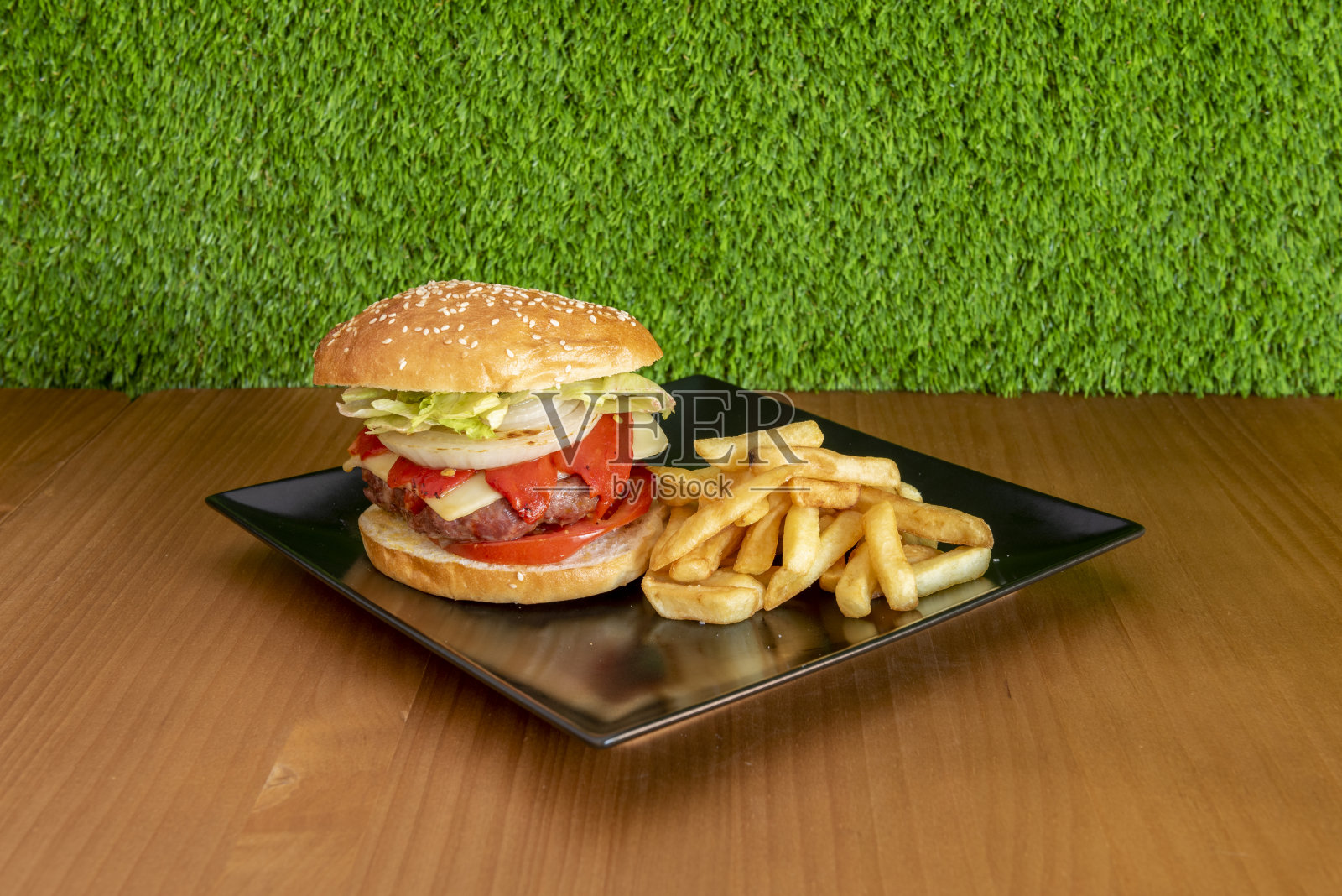 猪肉汉堡配芝士、皮基洛辣椒、番茄片、白洋葱圈、卷心莴苣和一份炸薯条照片摄影图片