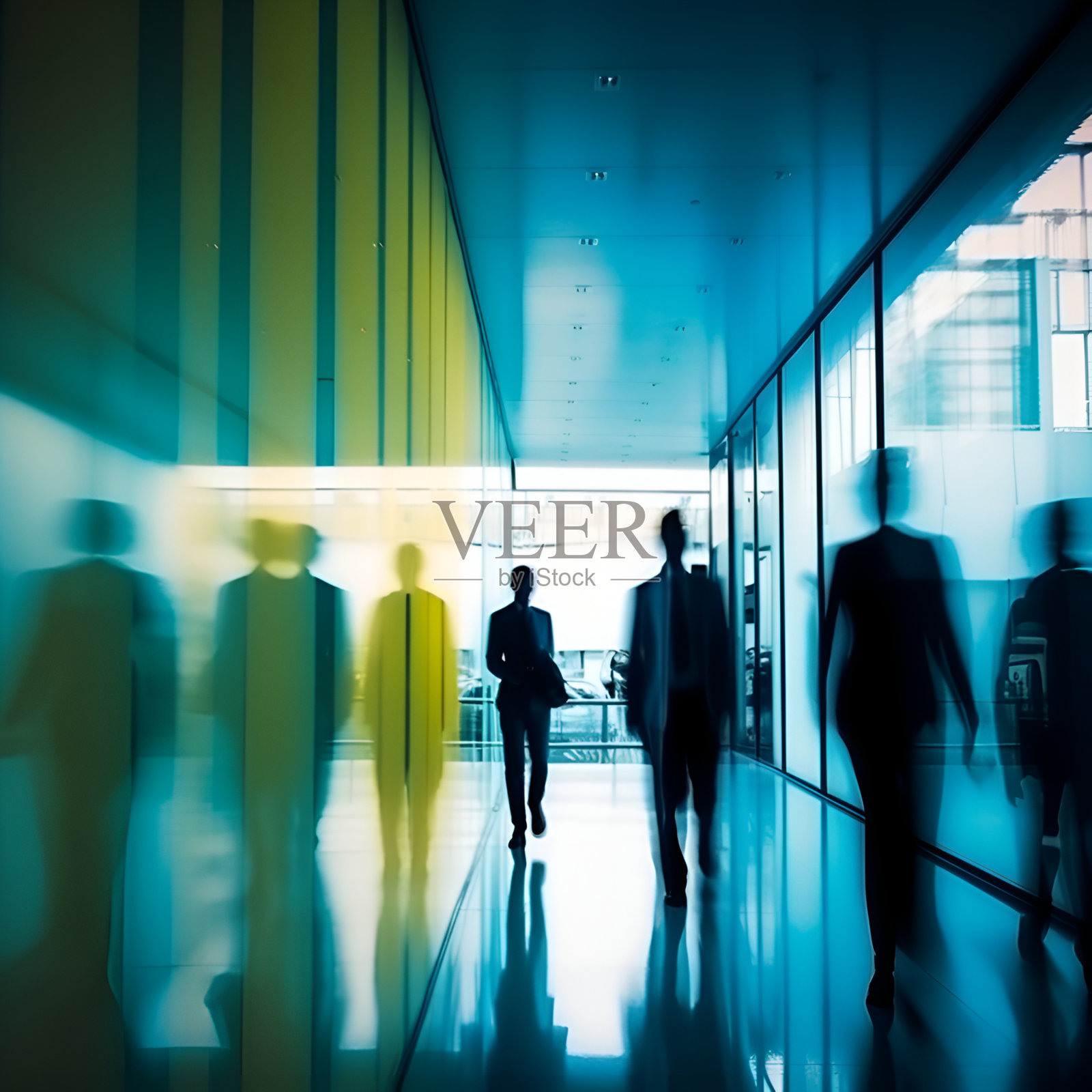 在蓝色和黄色的配色方案中,商业大楼内办公室员工的剪影融入了朦胧的模糊之中。照片摄影图片