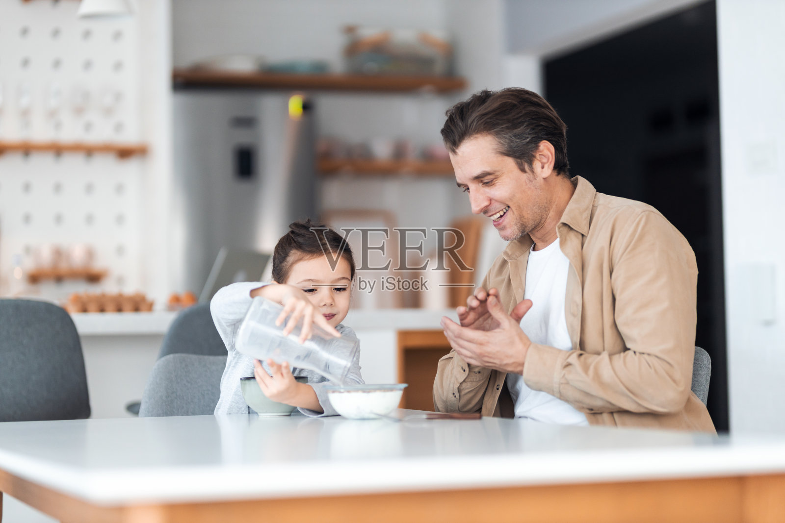 一个可爱的小女孩给爸爸做了牛奶麦片当早餐。照片摄影图片