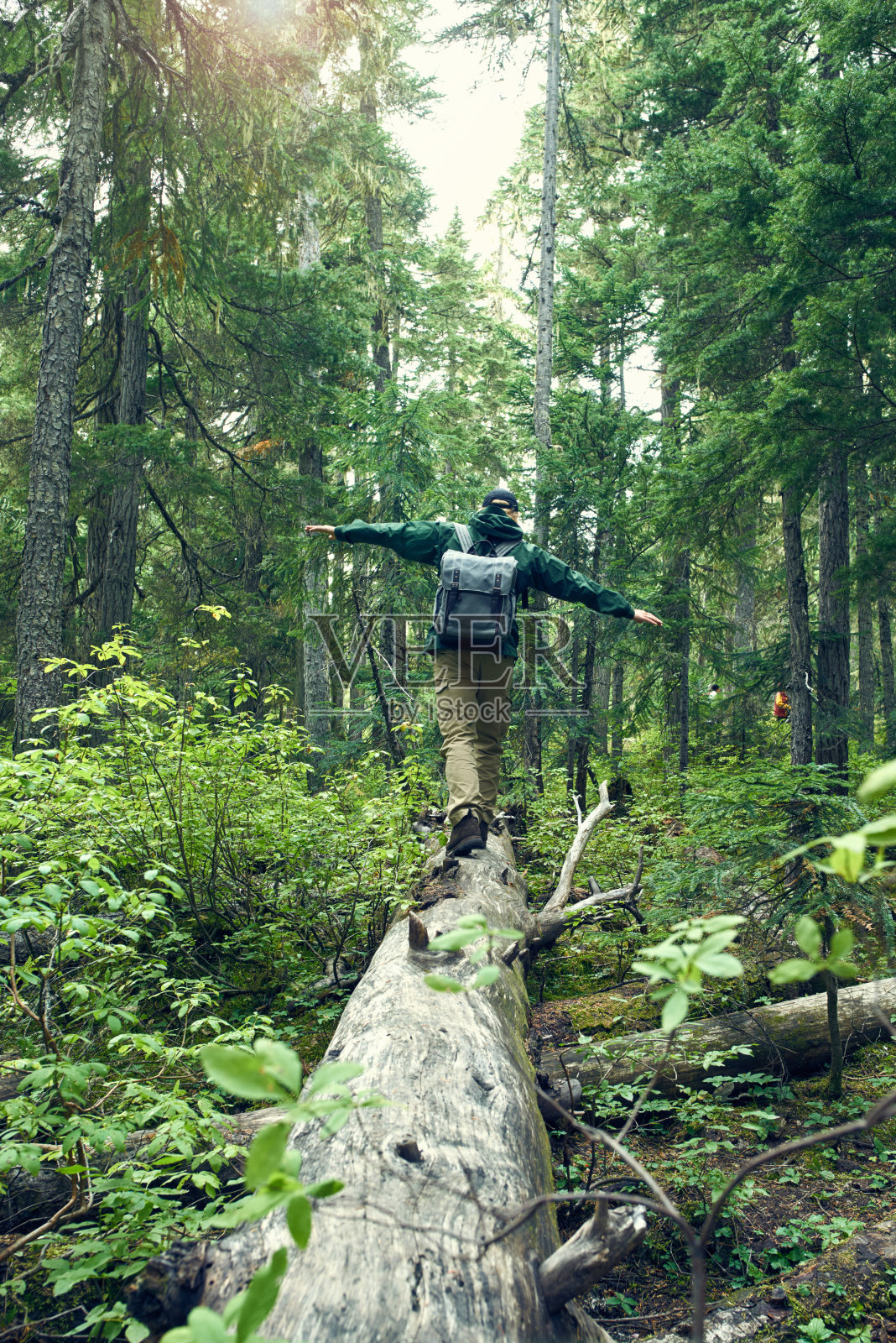 一个年轻人背着背包走在原木上的镜头照片摄影图片