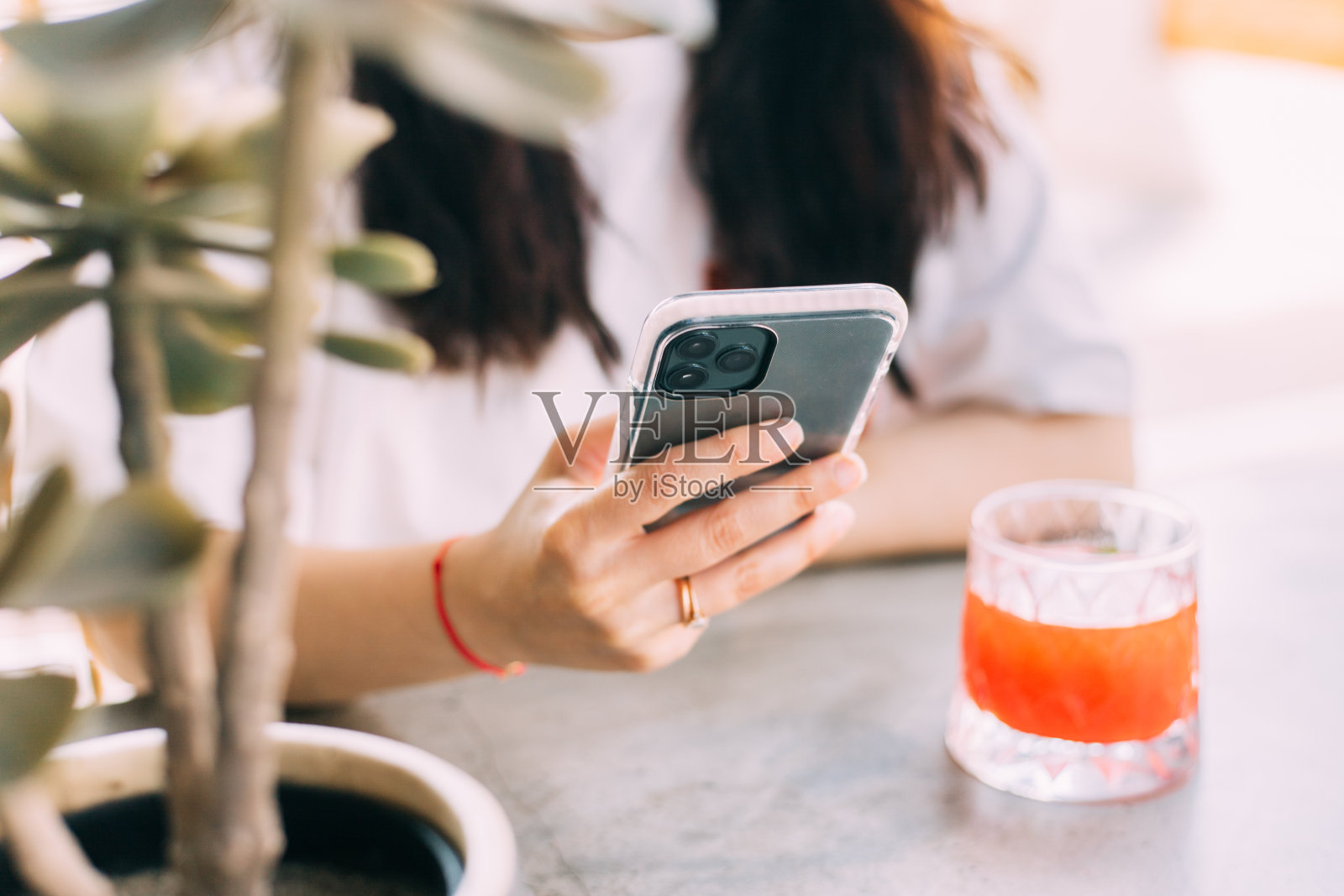女士一边喝草莓柠檬水一边用智能手机看视频照片摄影图片