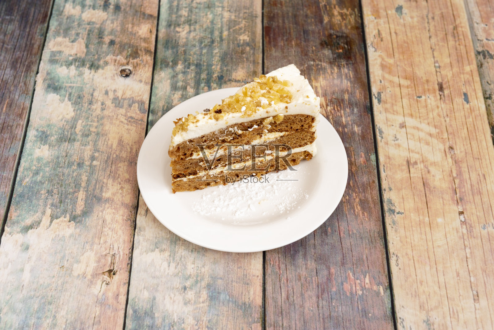 美味的胡萝卜蛋糕,三层海绵蛋糕,两层夹心,一层覆盖坚果和糖粉,放在白色盘子里照片摄影图片